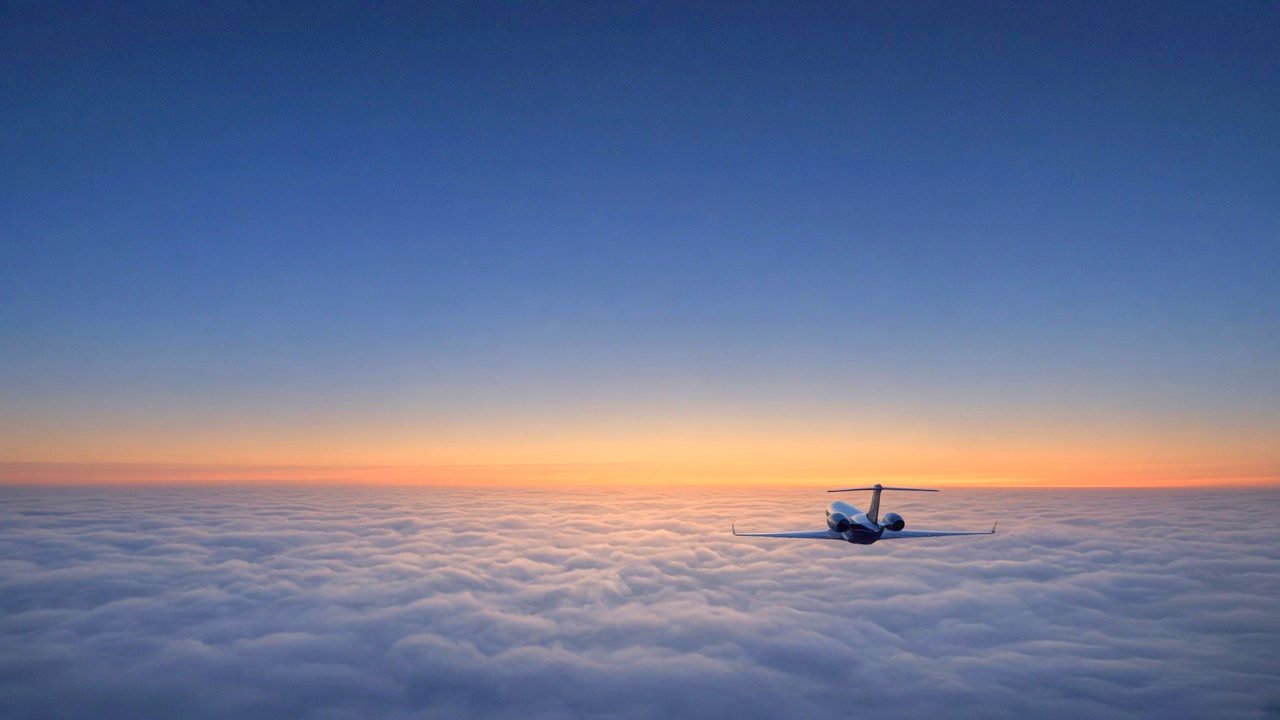Private jet flying above the clouds at sunset