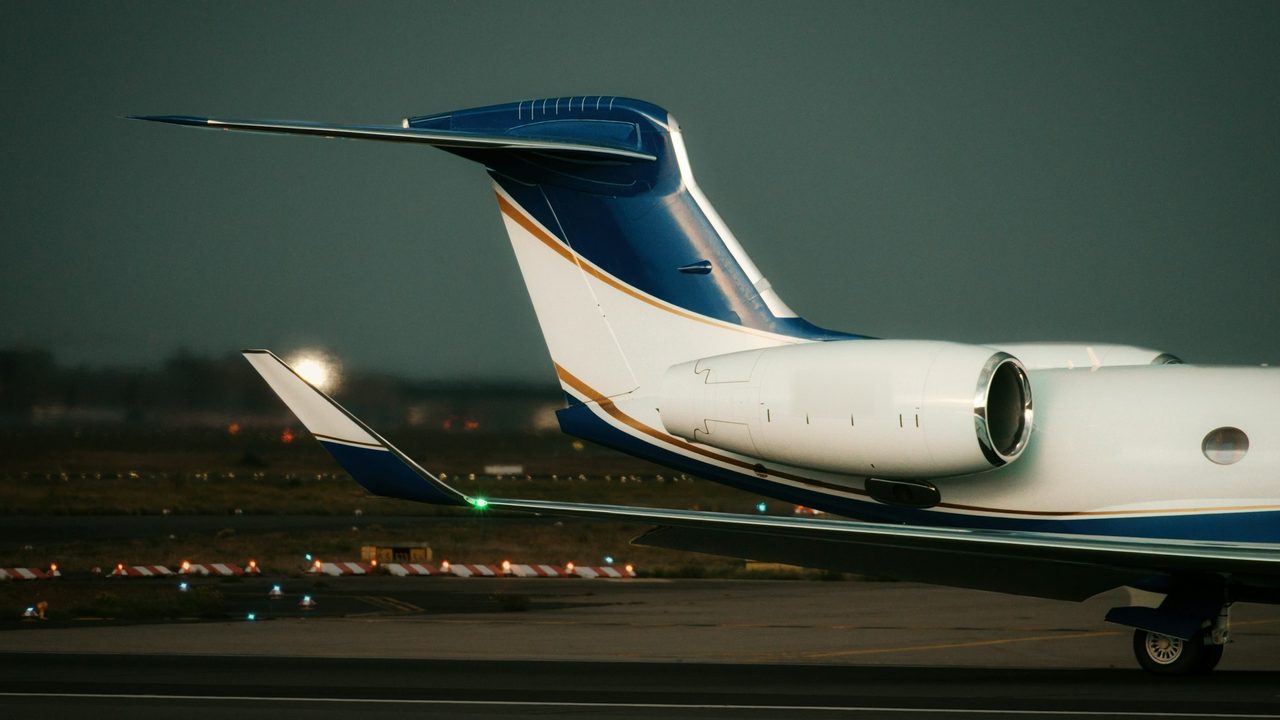 Tail and engine of a private jet on the taxiway at dusk